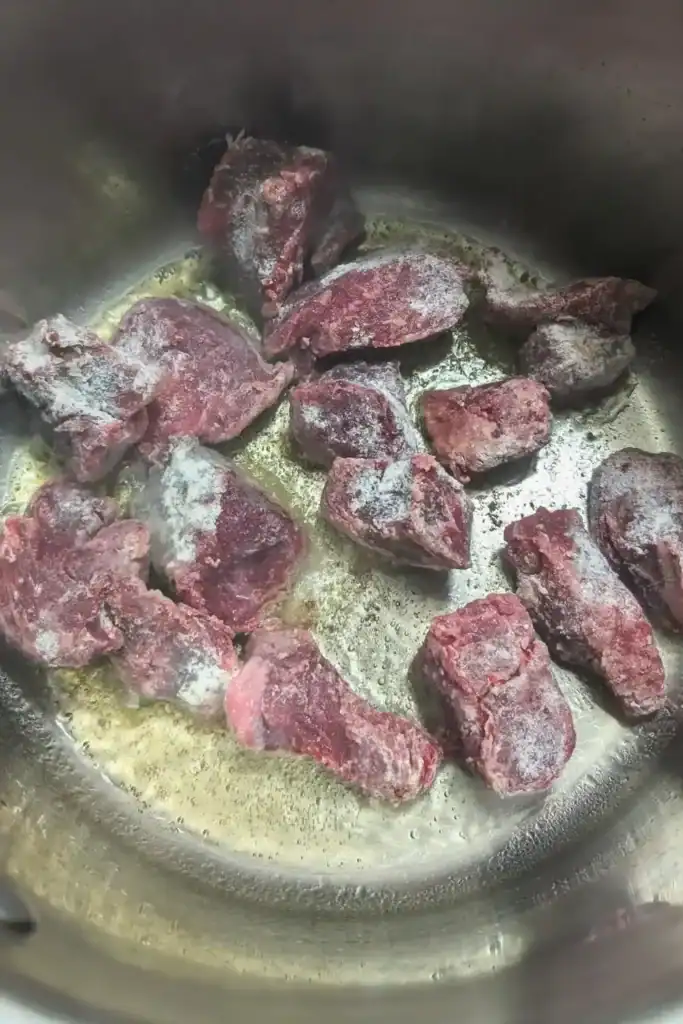 adding floured stew meat to the pot