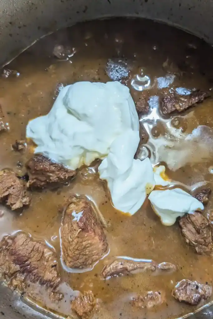adding the sour cream to the rich beef broth