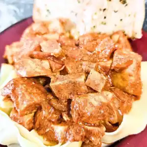 recipe card image of butter chicken pasta with toast on plate