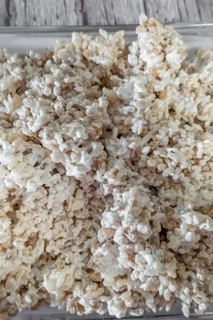 dumping the cereal marshmallow mixed mixture to the prepared pan
