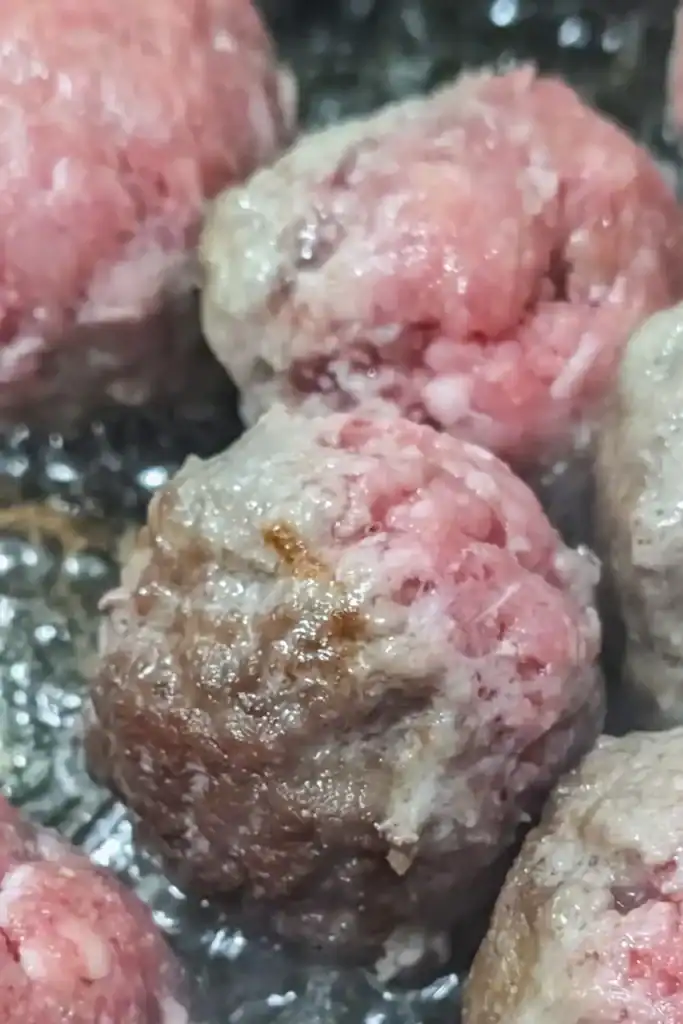 close of browning meatballs in neutral oil in non-stick frying pan