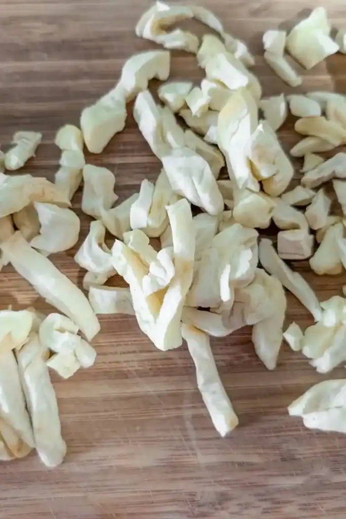 cut up dried apple rings on wooden cutting board