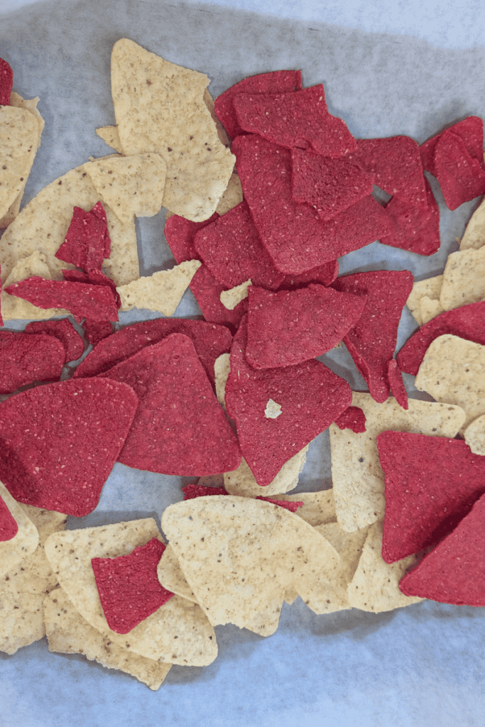 Colorful buffalo chicken nacho chips with red and beige tortilla pieces.