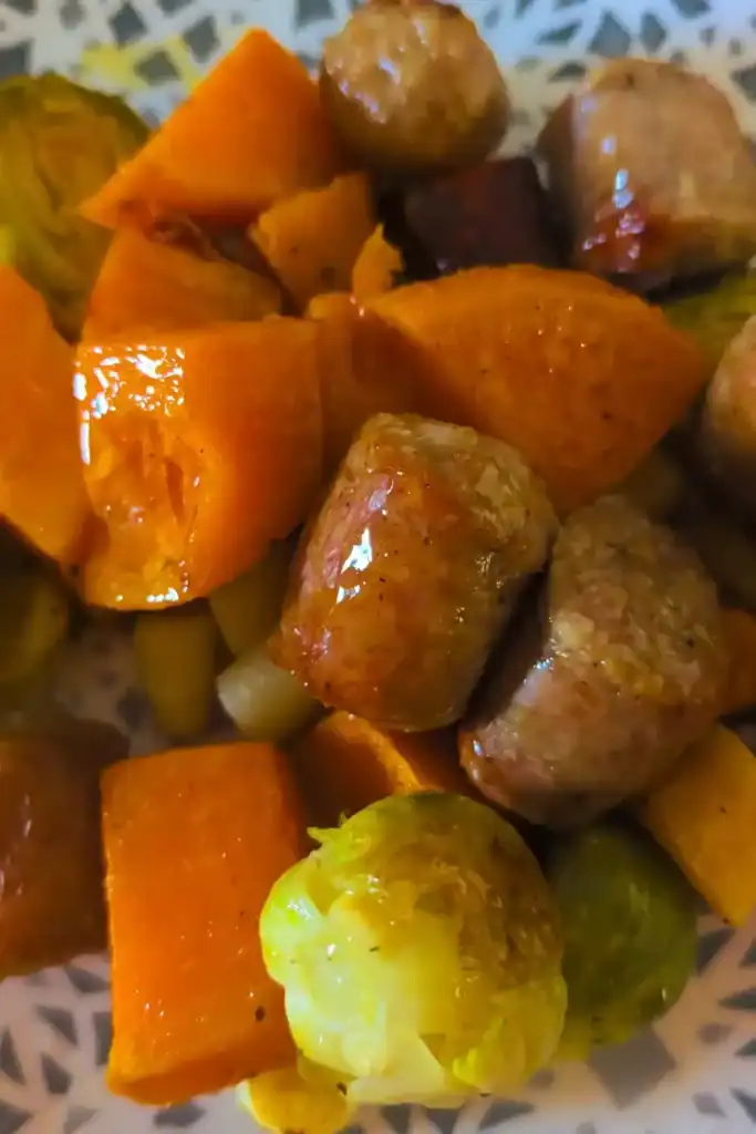 close up of glistening sausage and roasted veggies on blue and white patterned plate