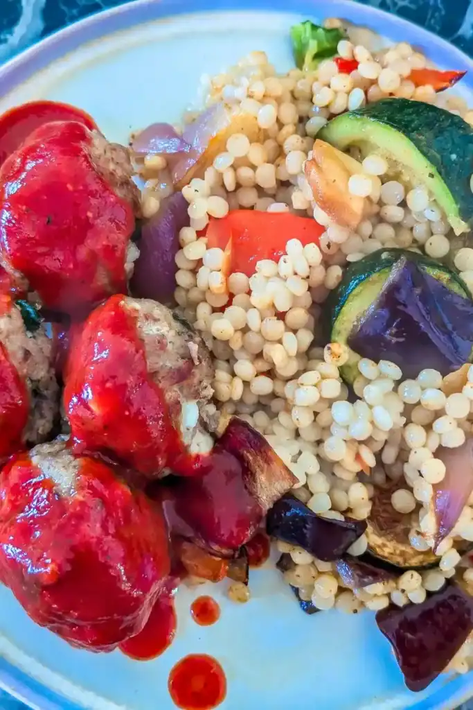the couscous side dish with turkey meatballs on beige plate