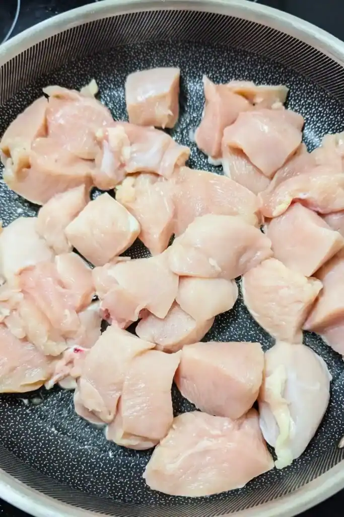 chicken breast pieces with olive oil in aluminum clad frying pan