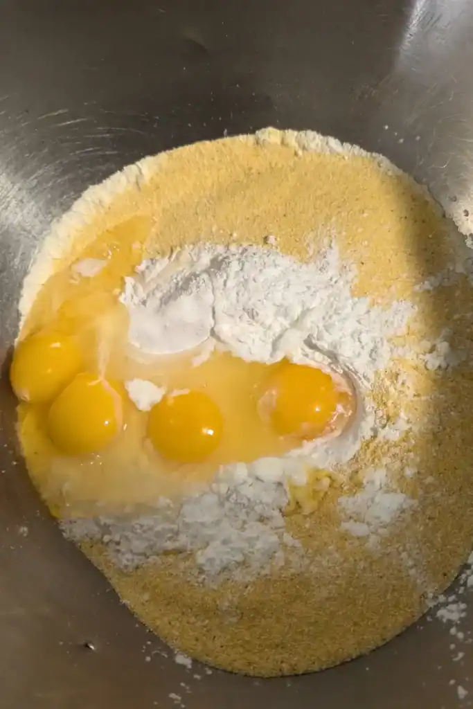 adding eggs to cornbread mixture in bowl