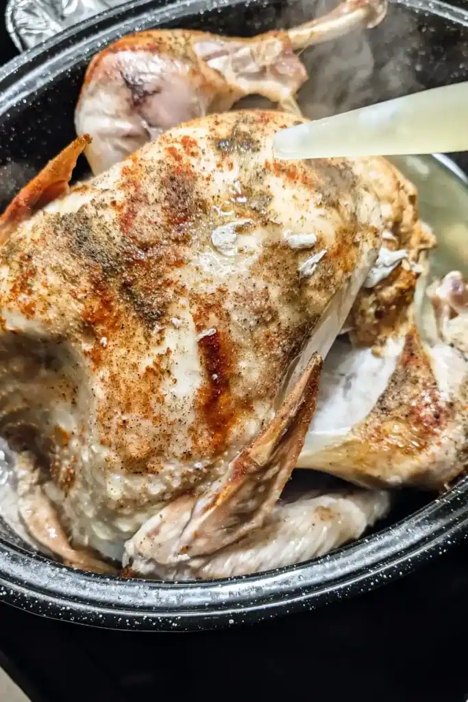 basting the spiced turkey in roasting pan