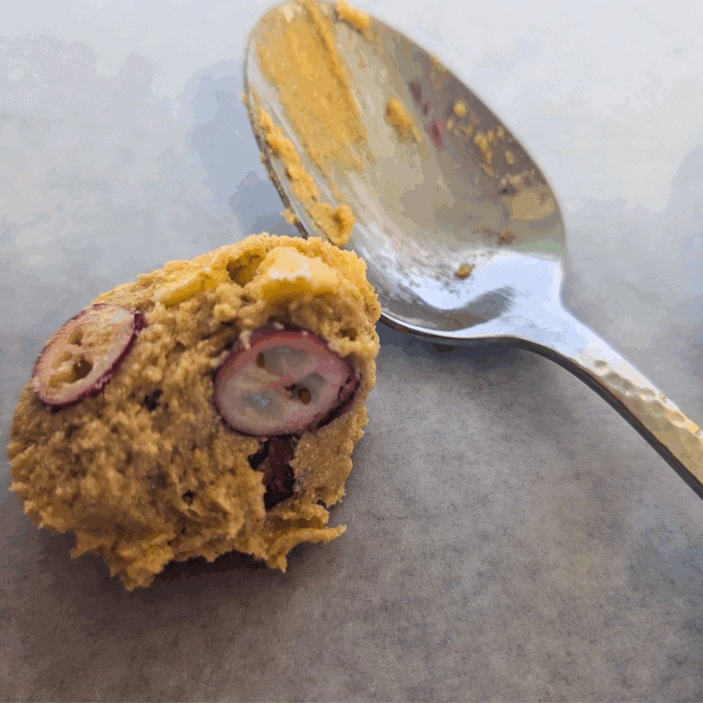 Egg sandwich and spoon on gray surface.