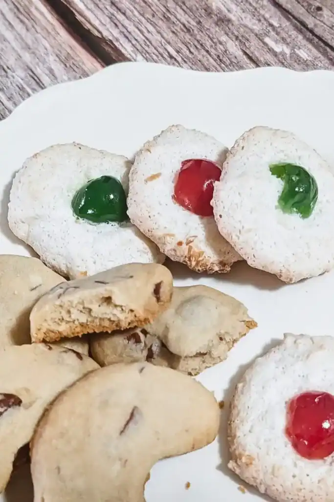 dessert plate with red and green cherried coconut macaroons and almond crescents