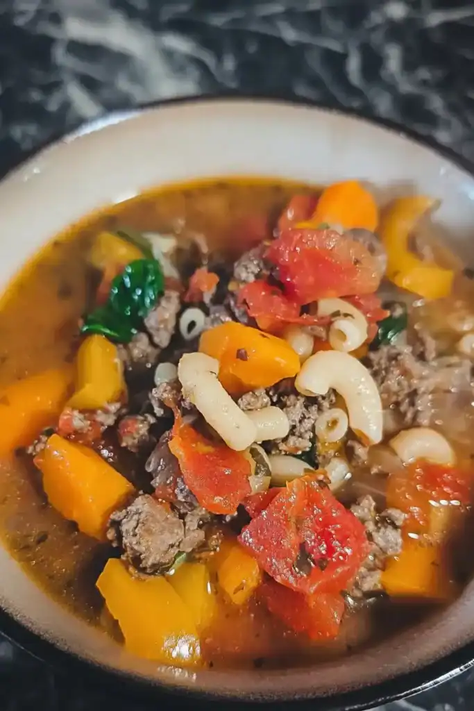 looking down on a bowl of hamburger soup on black marbled table