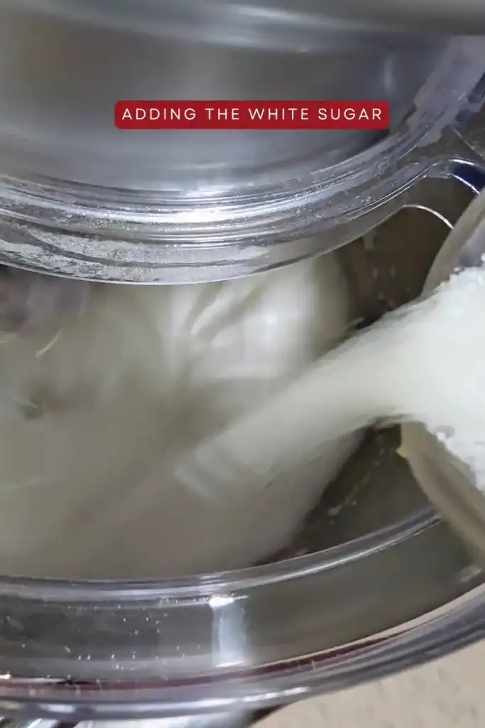 adding sugar to the egg white as they beat in the stand mixer