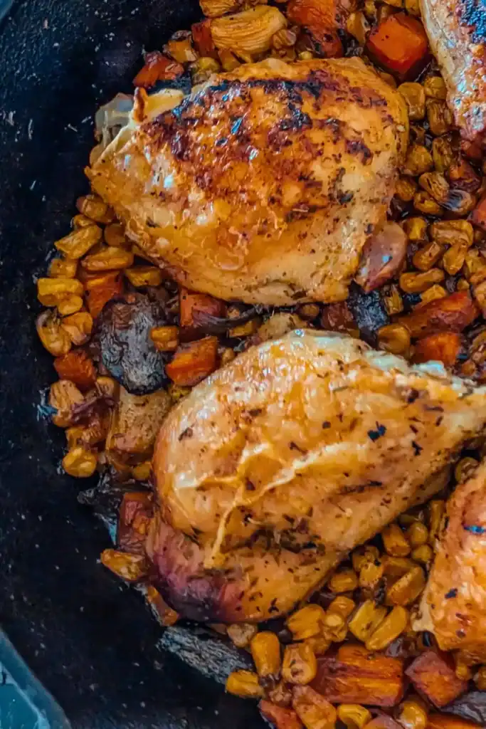 the baked chicken thighs in cast iron skillet on top of caramelized veggies