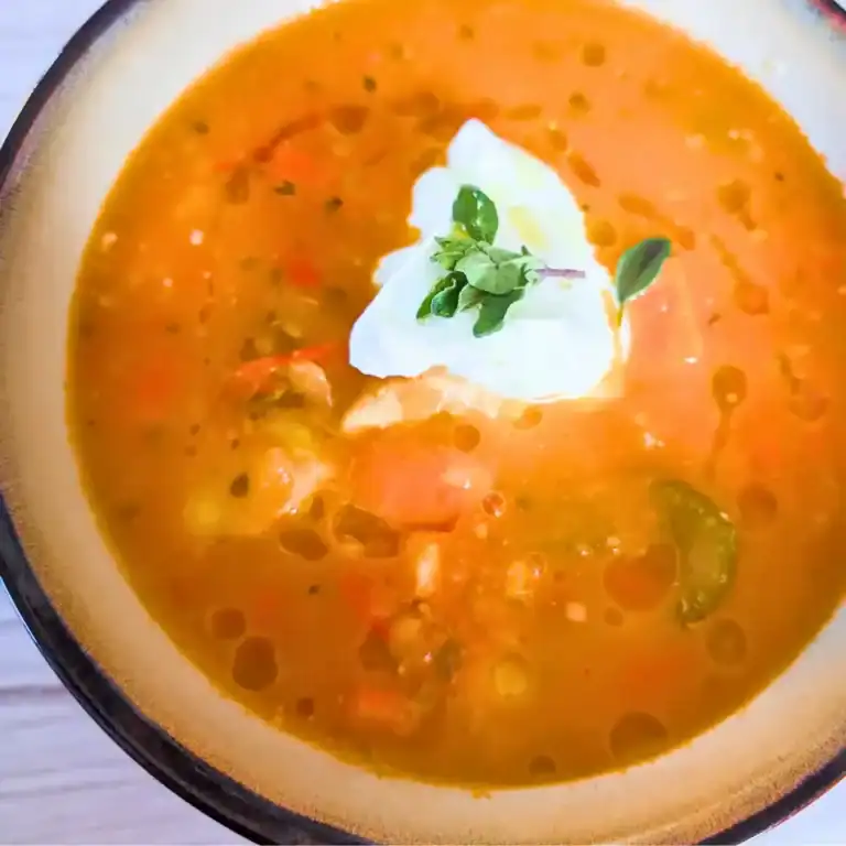 a bowlful of roast tomato chicken soup with vegetables and garnish