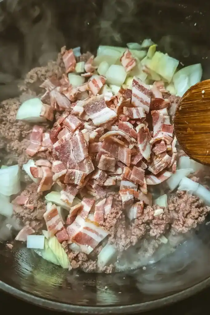 adding onion and precooked bacon pieces to beef