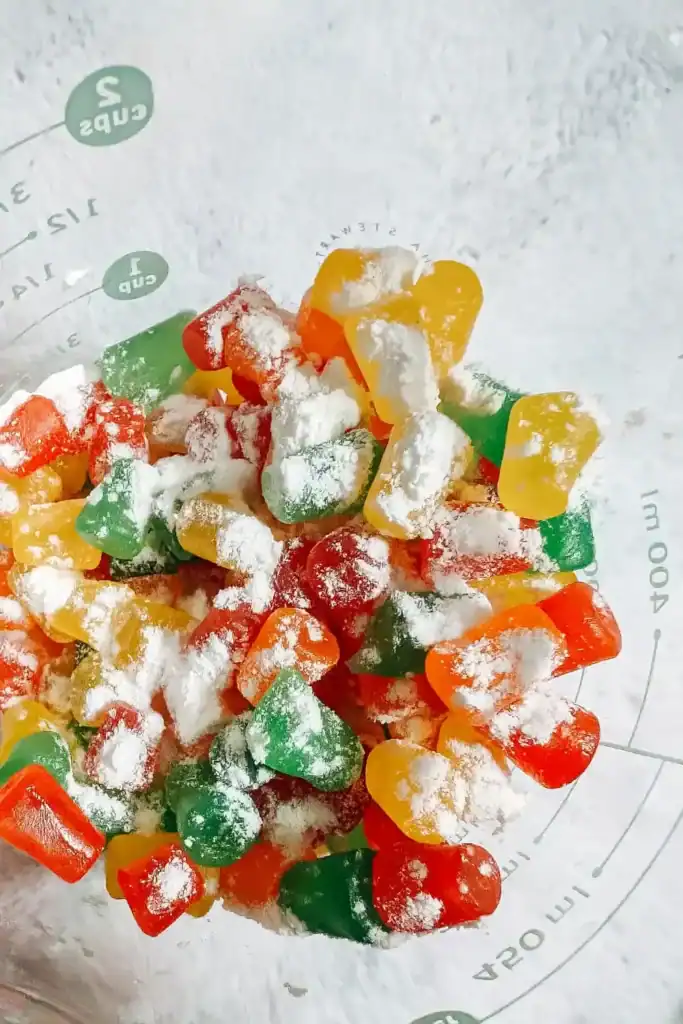 dusting gumdrops with flour in mixing bowl