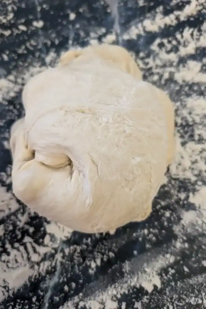 store-bought pizza dough ball on floured work surface