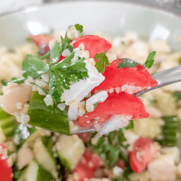 Close-up of Mediterranean bulgur and white bean salad with fresh herbs and vegetables.