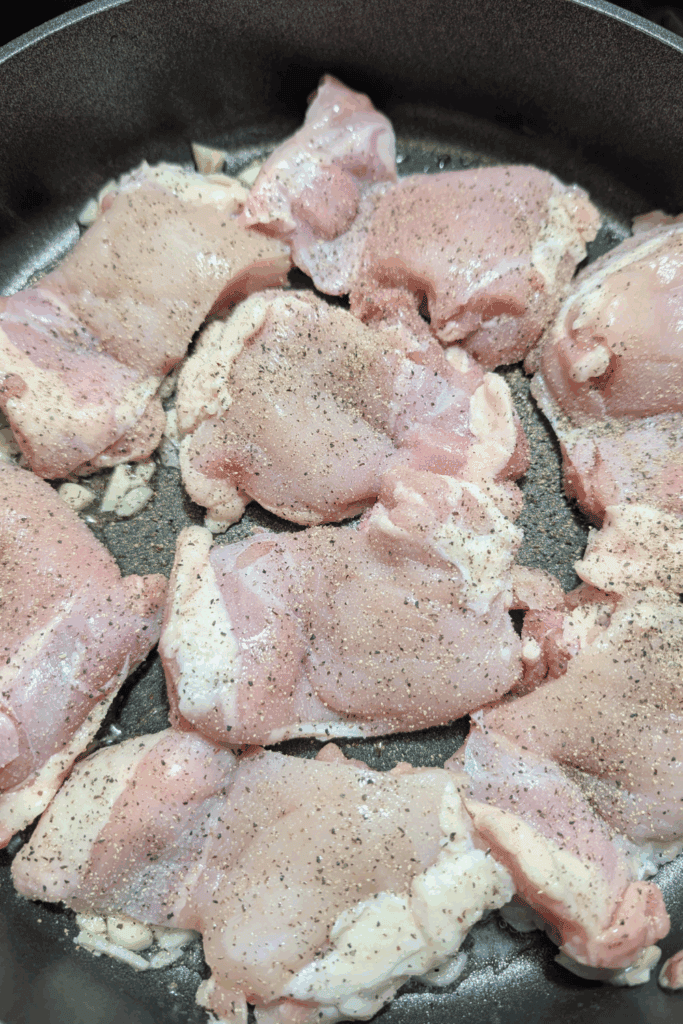 adding seasoning to chicken thighs in pan