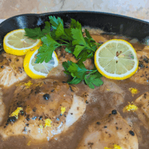 Fresh lemon chicken stew garnished with parsley in a skillet.