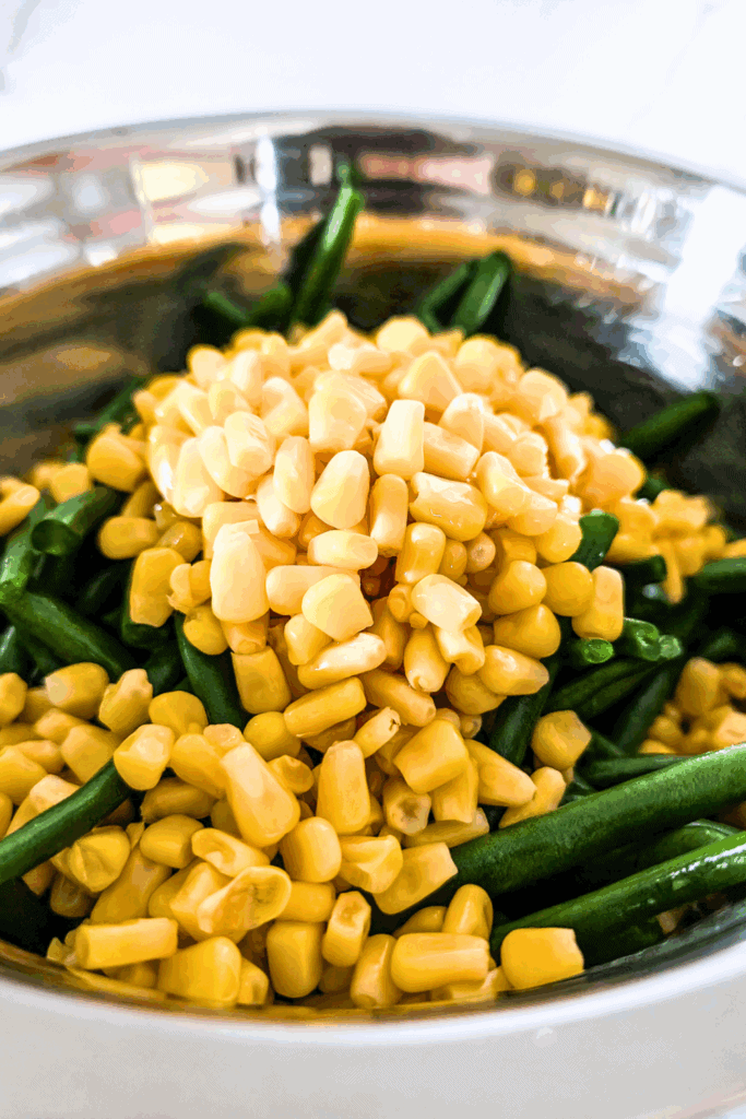 Yellow corn kernels and green beans in a stainless steel bowl for healthy vegetable recipes.