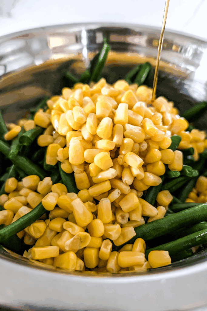 Corn and green beans being cooked in a stainless steel pot.