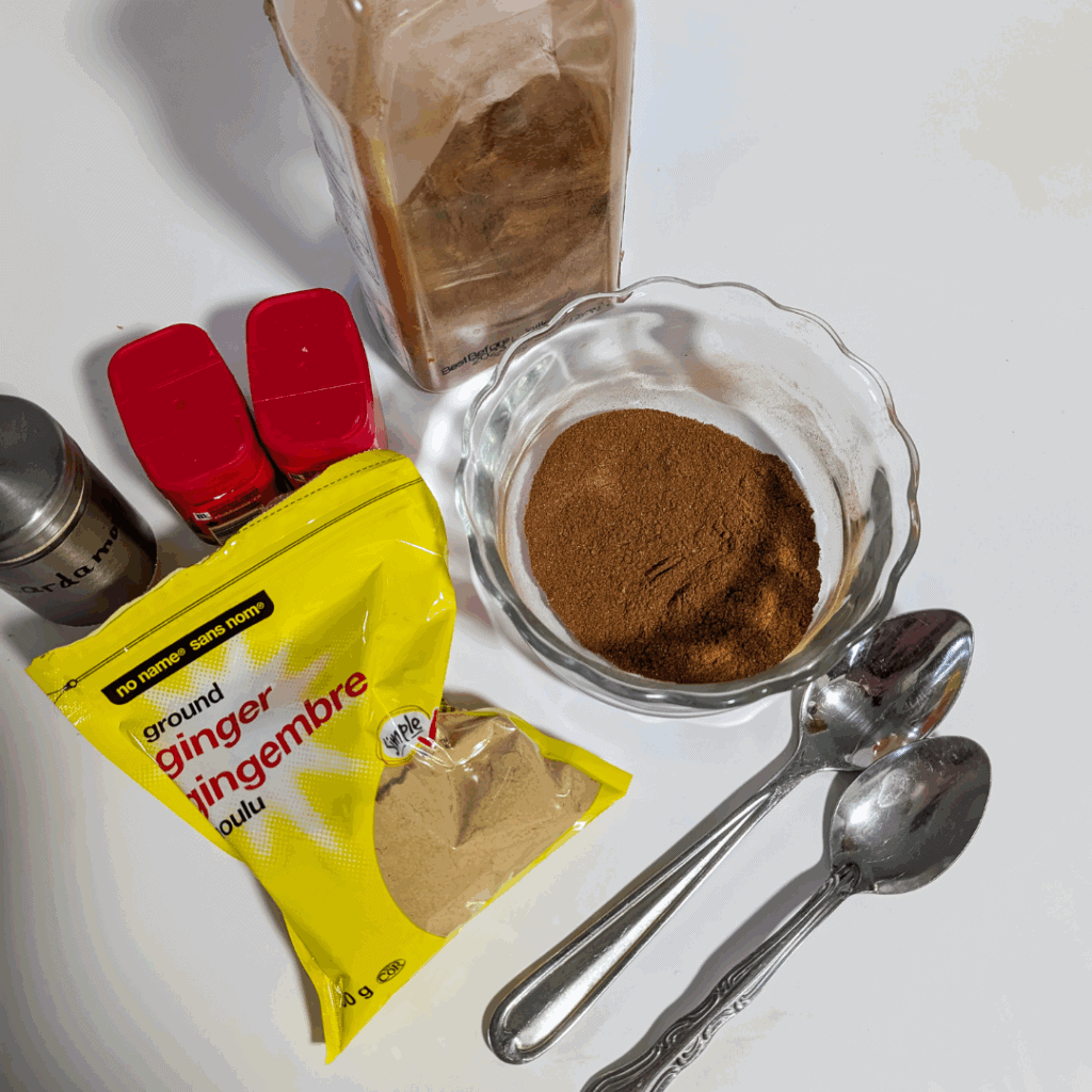 Ground cinnamon, ginger, and spices for baking or cooking, displayed with measuring spoons and ingredients on a white surface.