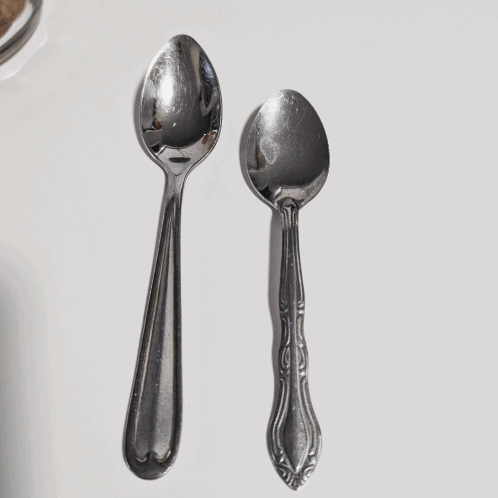 Shiny silver spoons on a white background, cooking utensils for culinary use.