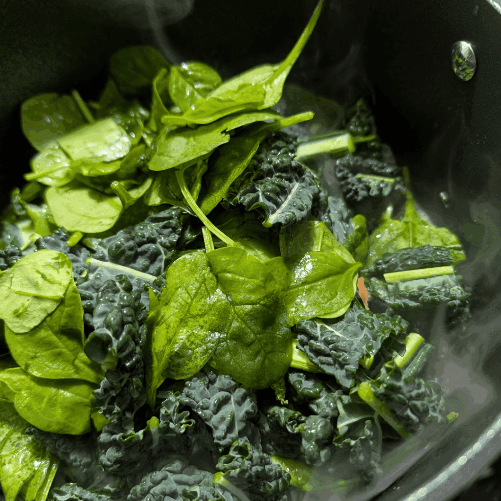Fresh kale and spinach greens in a cooking pot for healthy recipes.