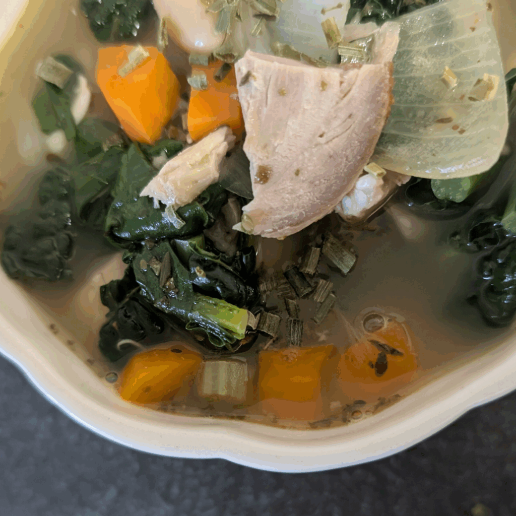 Beef and vegetable soup with carrots and kale in a creamy broth.