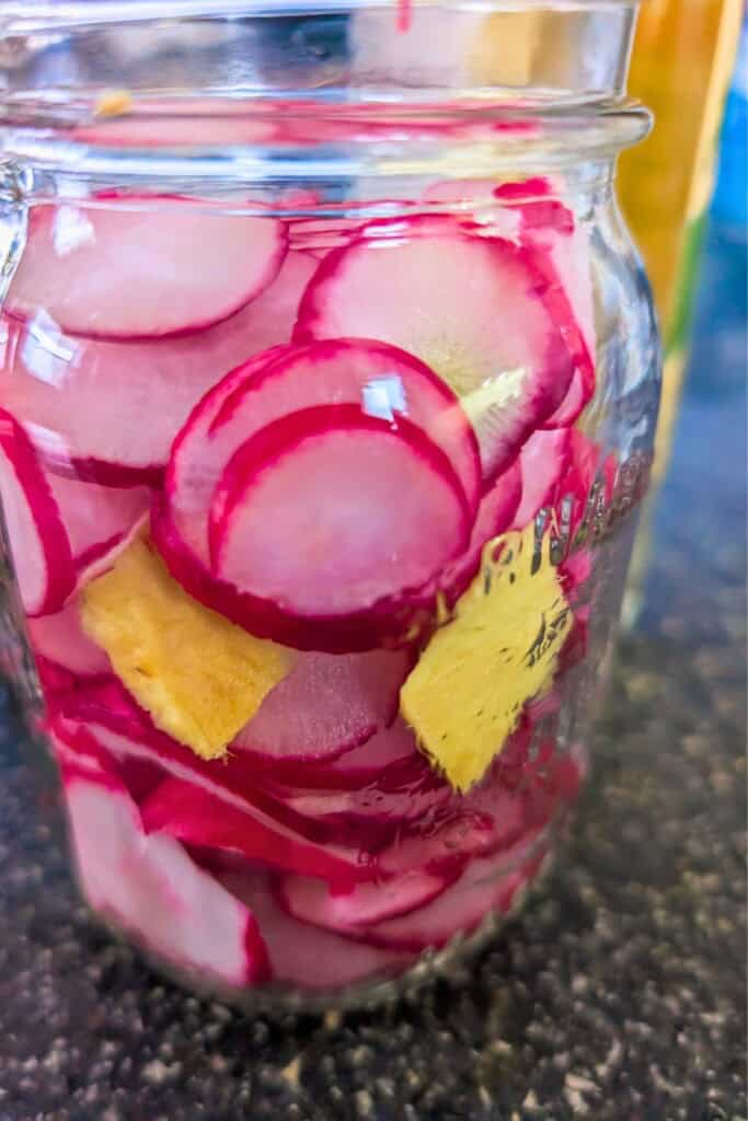 Quick pickled radishes in a glass jar for easy recipe preparation.