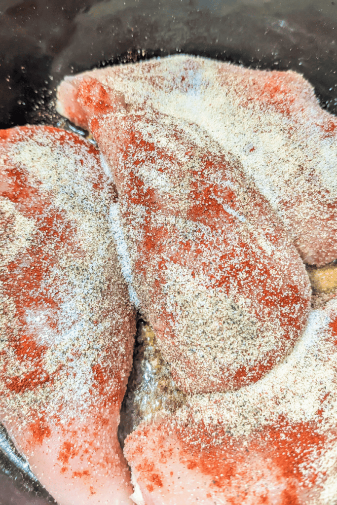 Shredded chicken breasts seasoned and cooked in a Dutch oven for quick meal prep. Perfect for health.
