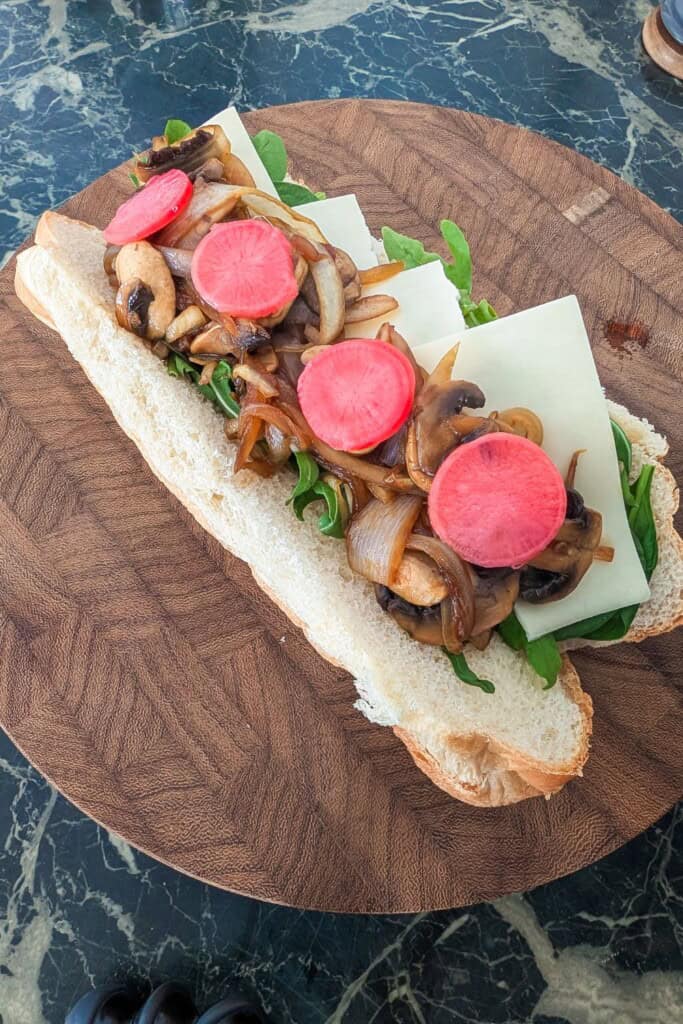 Delicious sandwich with pickled radishes, mushrooms, and greens on toasted bread.