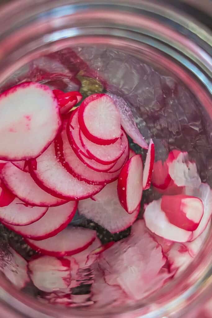 Radishes being sliced for quick pickled radishes in 30 minutes.