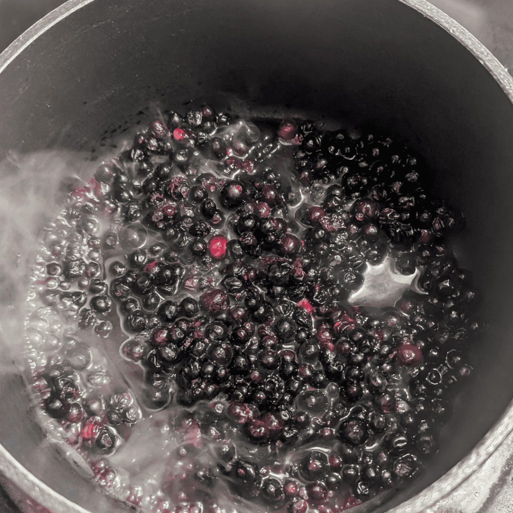 Cooking blueberries for blueberry ice cream recipe in a pot.