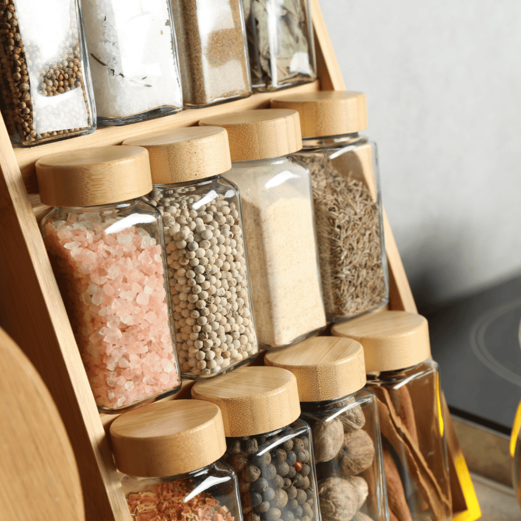 Salt and spice jars on a wooden rack for cooking and seasoning.