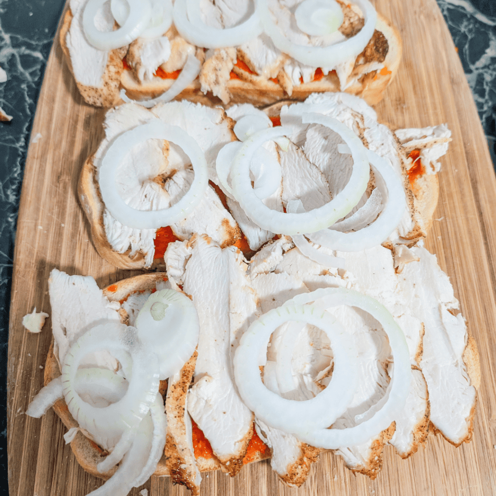 Open-faced sandwiches with onions, tomatoes, and bread.