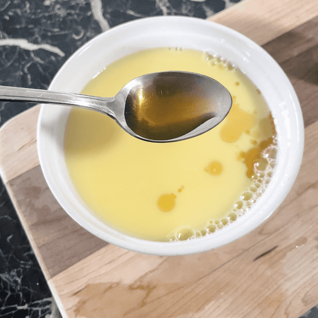 Freshly prepared lemon honey tea in a white cup with a spoon.