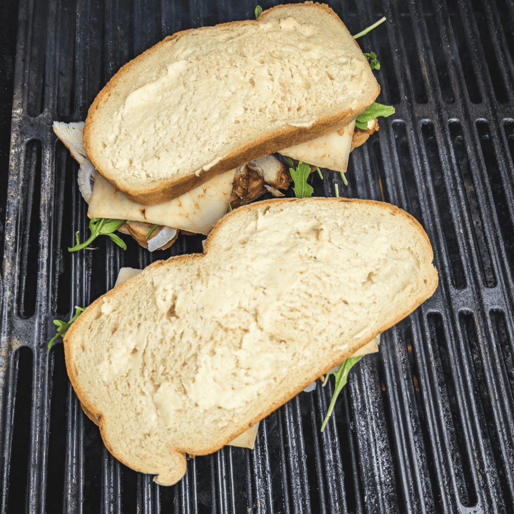 Delicious grilled cheese sandwich with melted cheese on toasted bread on a black grill pan.