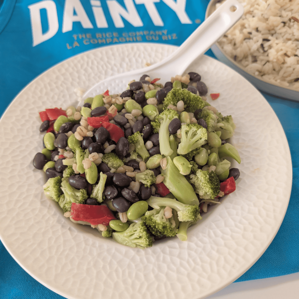 Colorful vegetable salad with broccoli, red peppers, and black beans on a white plate.