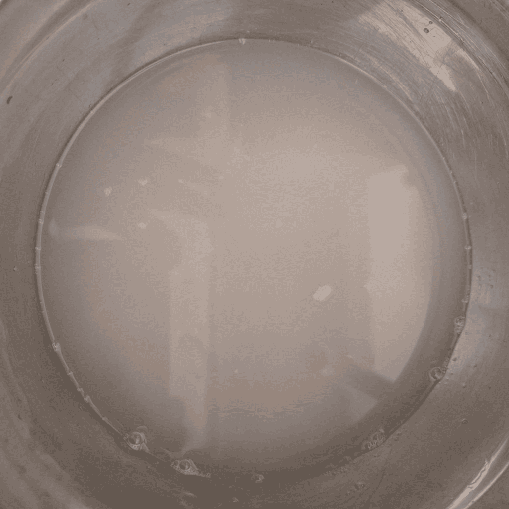 Creamy milk mixture in a stainless steel bowl for cooking or baking.