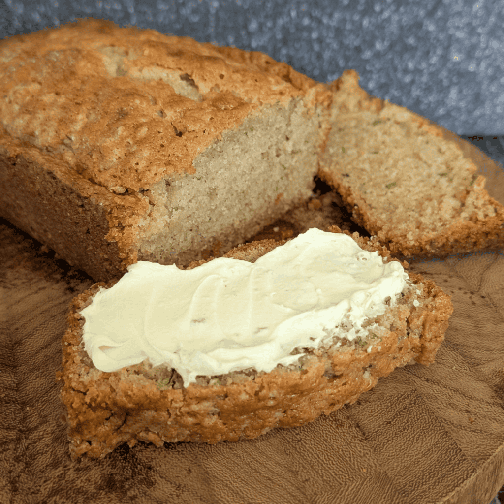 Fresh homemade banana bread with butter spread on a wooden surface.