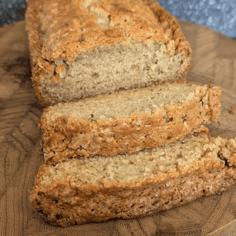 Delicious homemade zucchini bread sliced on a wooden cutting board.