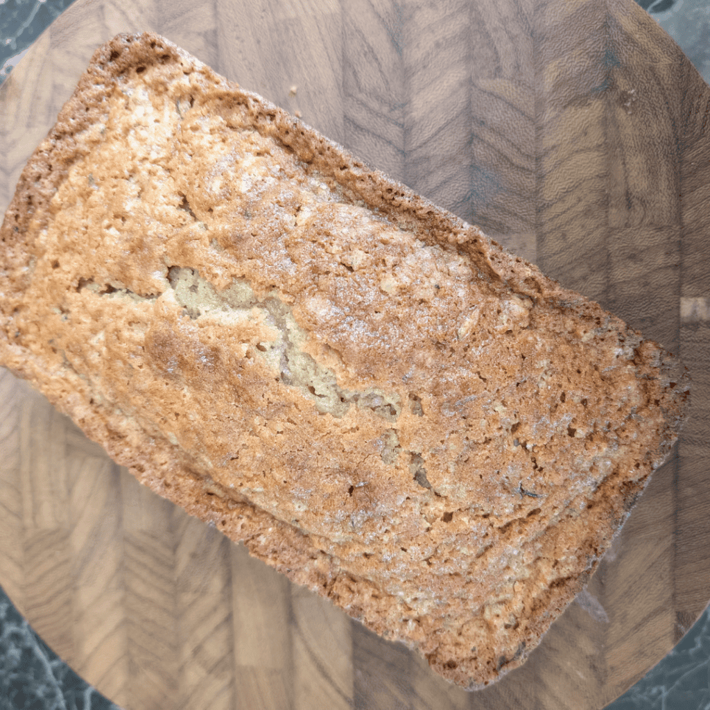 Freshly baked banana bread loaf on a wooden cutting board.