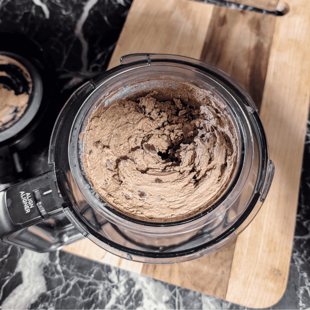 double chocolate ice cream in ninja creami pint in the base on a wooden cutting board