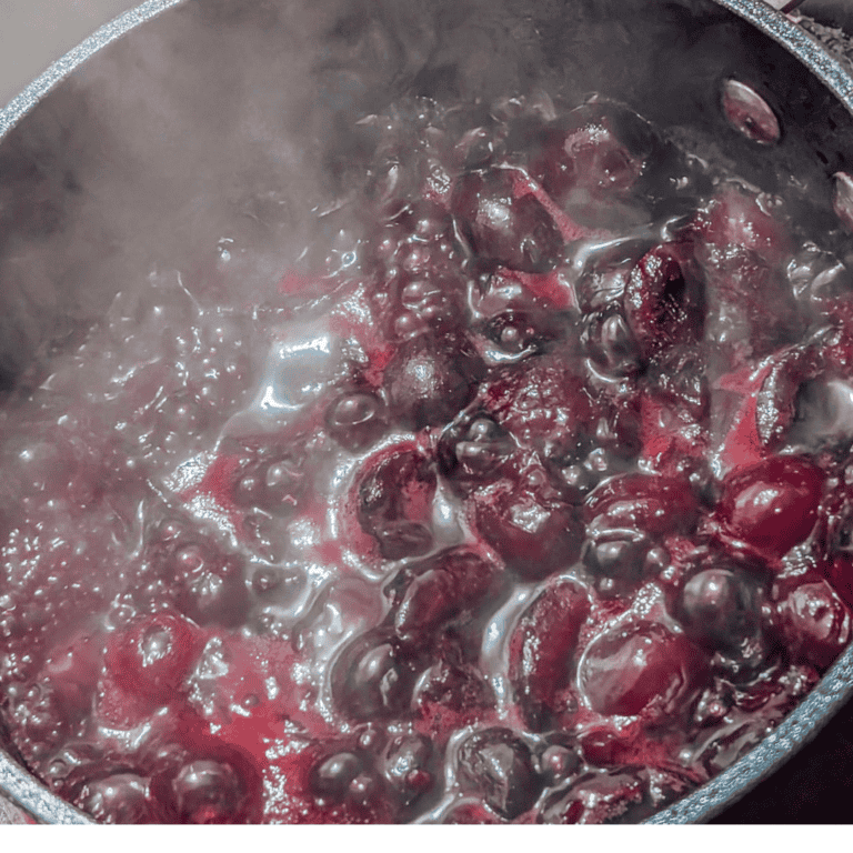 Boiling fresh cherries in a pot for homemade cherry jam or syrup.