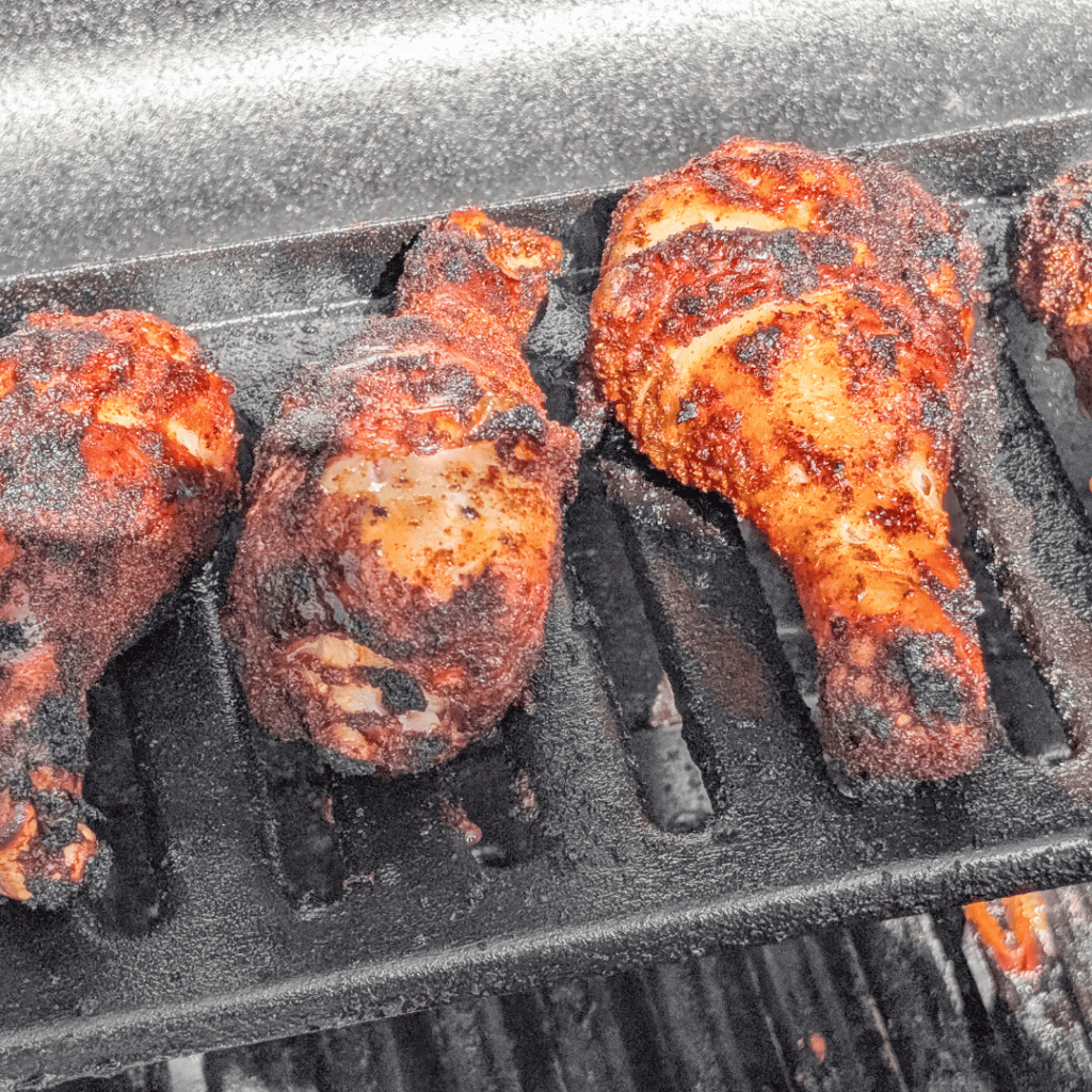 Grilled BBQ chicken drumsticks with smoky spice rub on a barbecue grill.