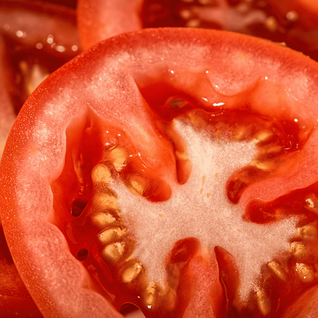 Close-up of a ripe tomato sliced open showing seeds and flesh.