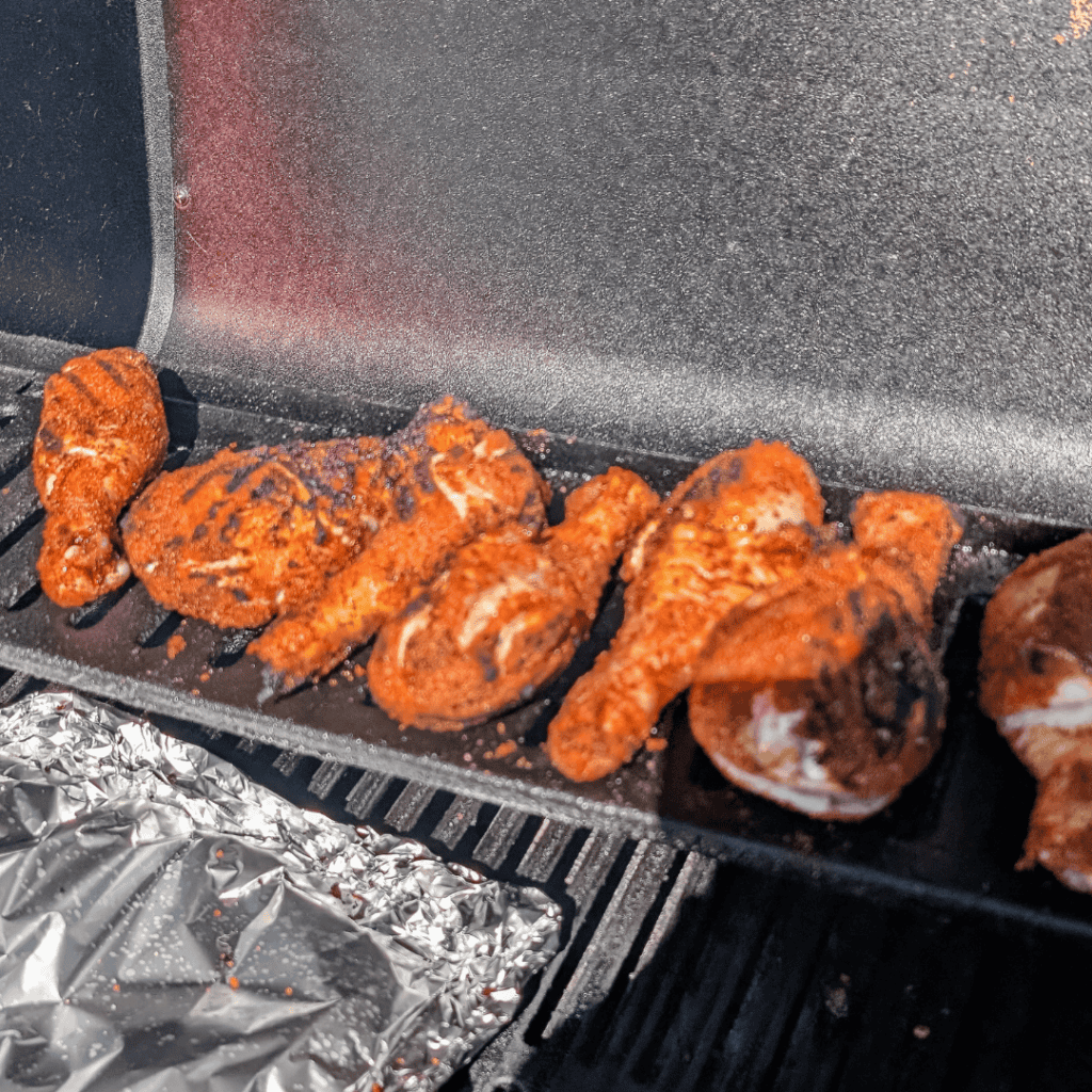 Grilled chicken drumsticks with smoky spice rub on barbecue grill.