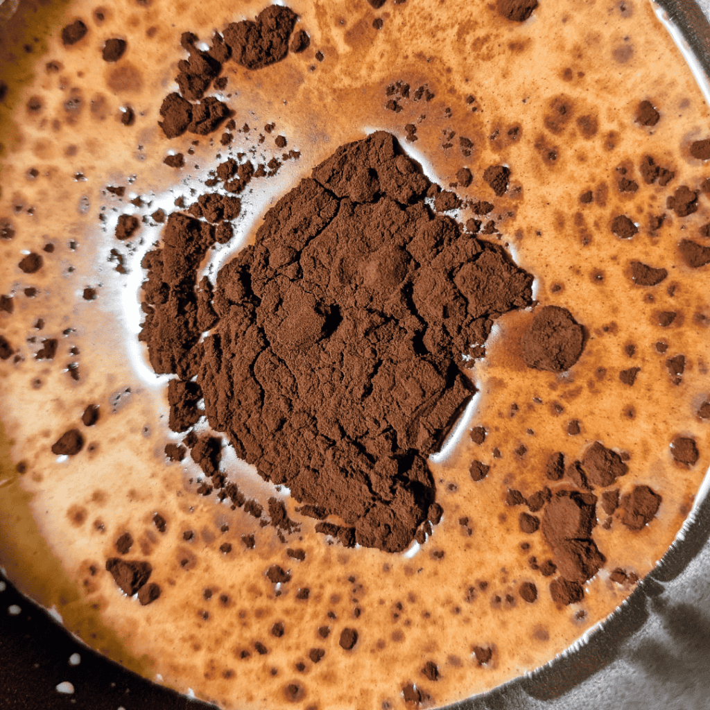 red alkalyzed cocoa powder in half and half cream in saucepan